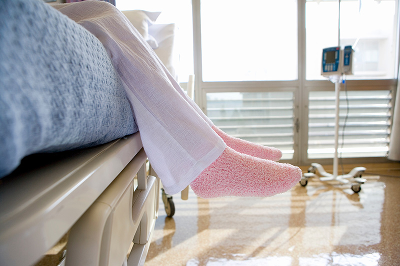Feet in socks dangling over a hospital bed.