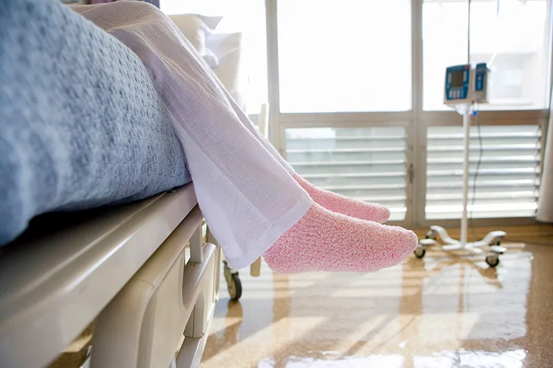 Feet in socks dangling over a hospital bed.