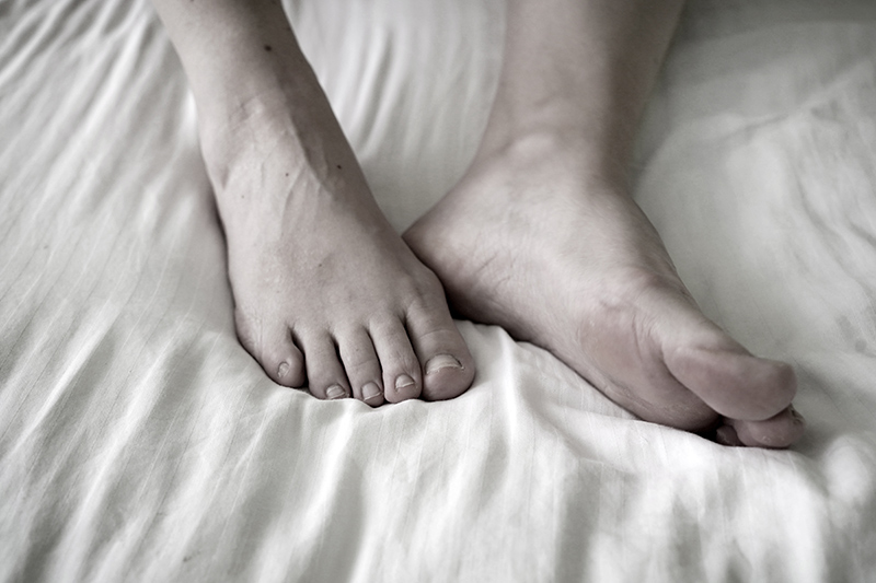 Recovering feet resting on a bed.