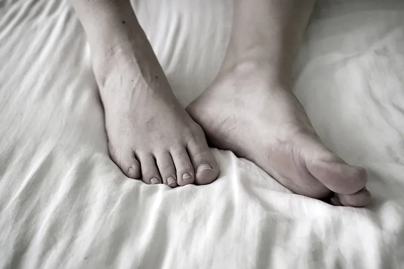 Recovering feet resting on a bed.