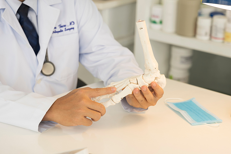 Bunion doctor in Singapore using a foot model to explain treatment options to a patient